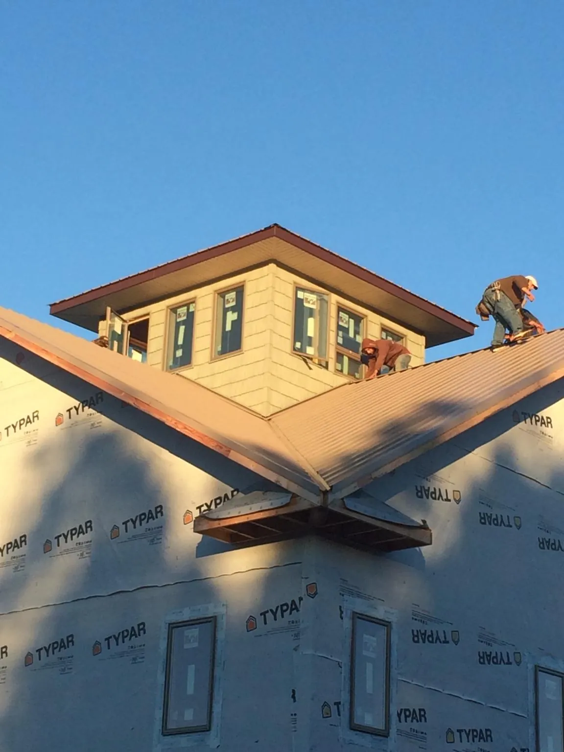 Roofers working around a rooftop cupola on a new metal roof at sunset — Roof Waterproofing in Lincoln by Roofing Brothers